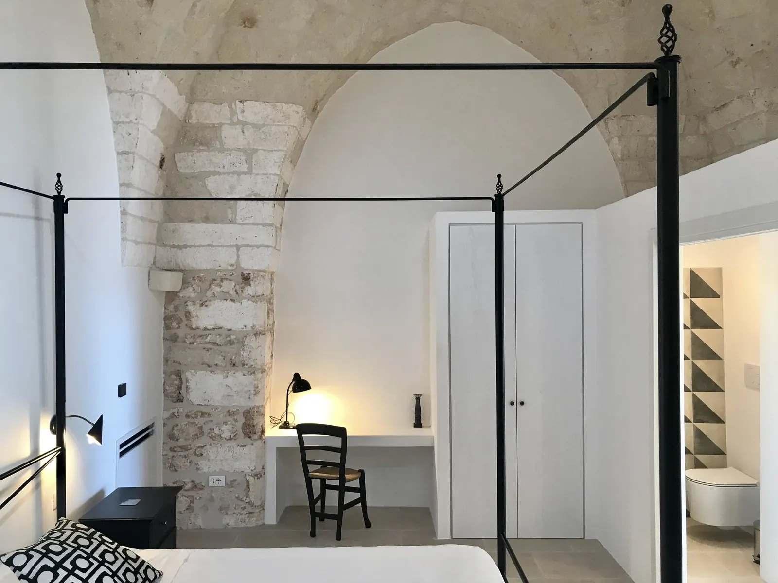 Bedroom with four-poster bed under a stone vault