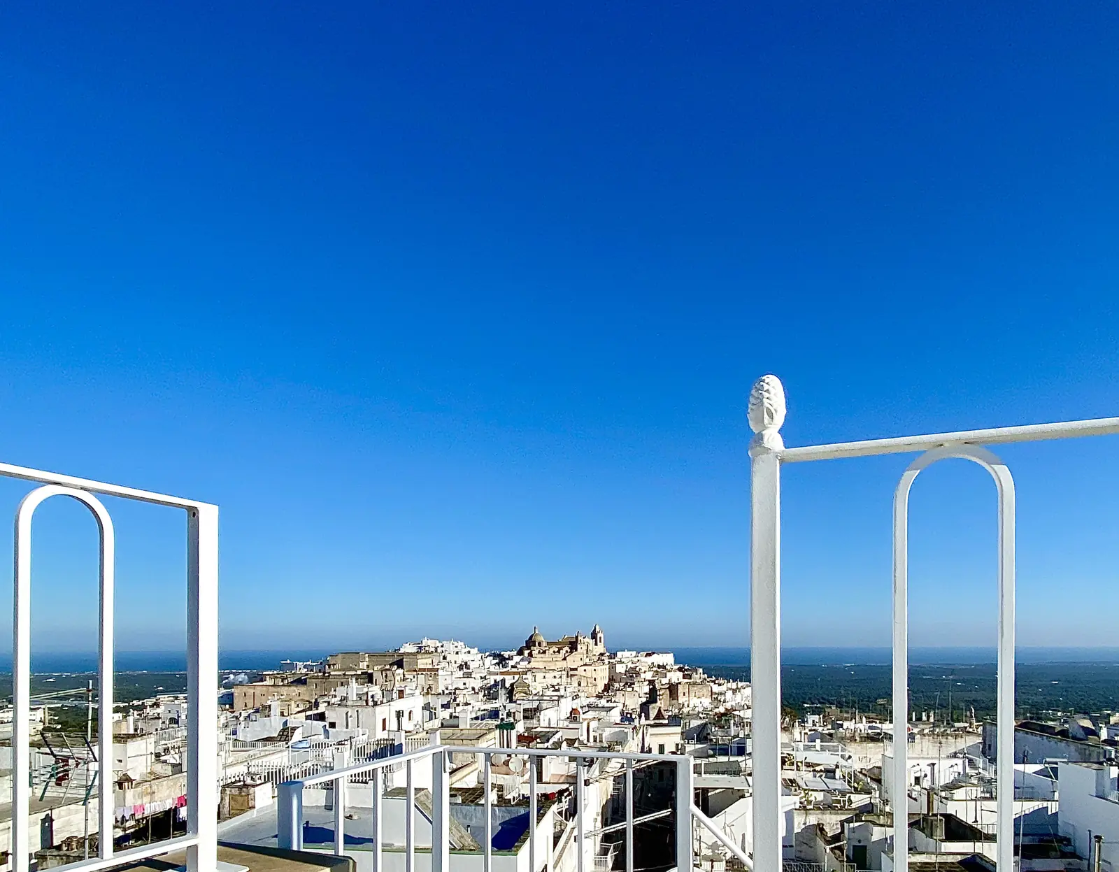 The old town and cathedral framed by the white terrace railings, with the sea beyond