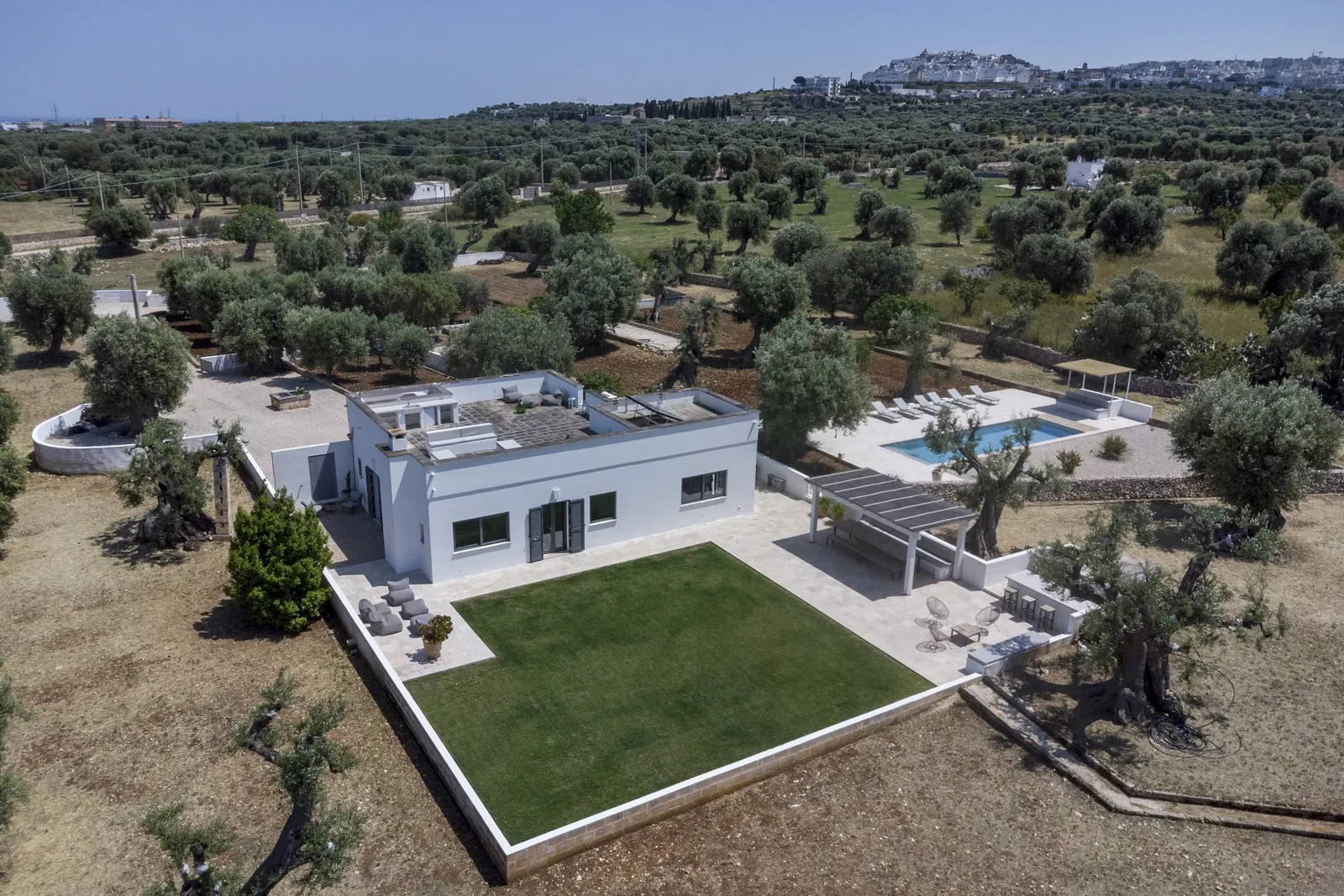 Aerial view of Casa Emilia among the olive groves, with Ostuni on the horizon