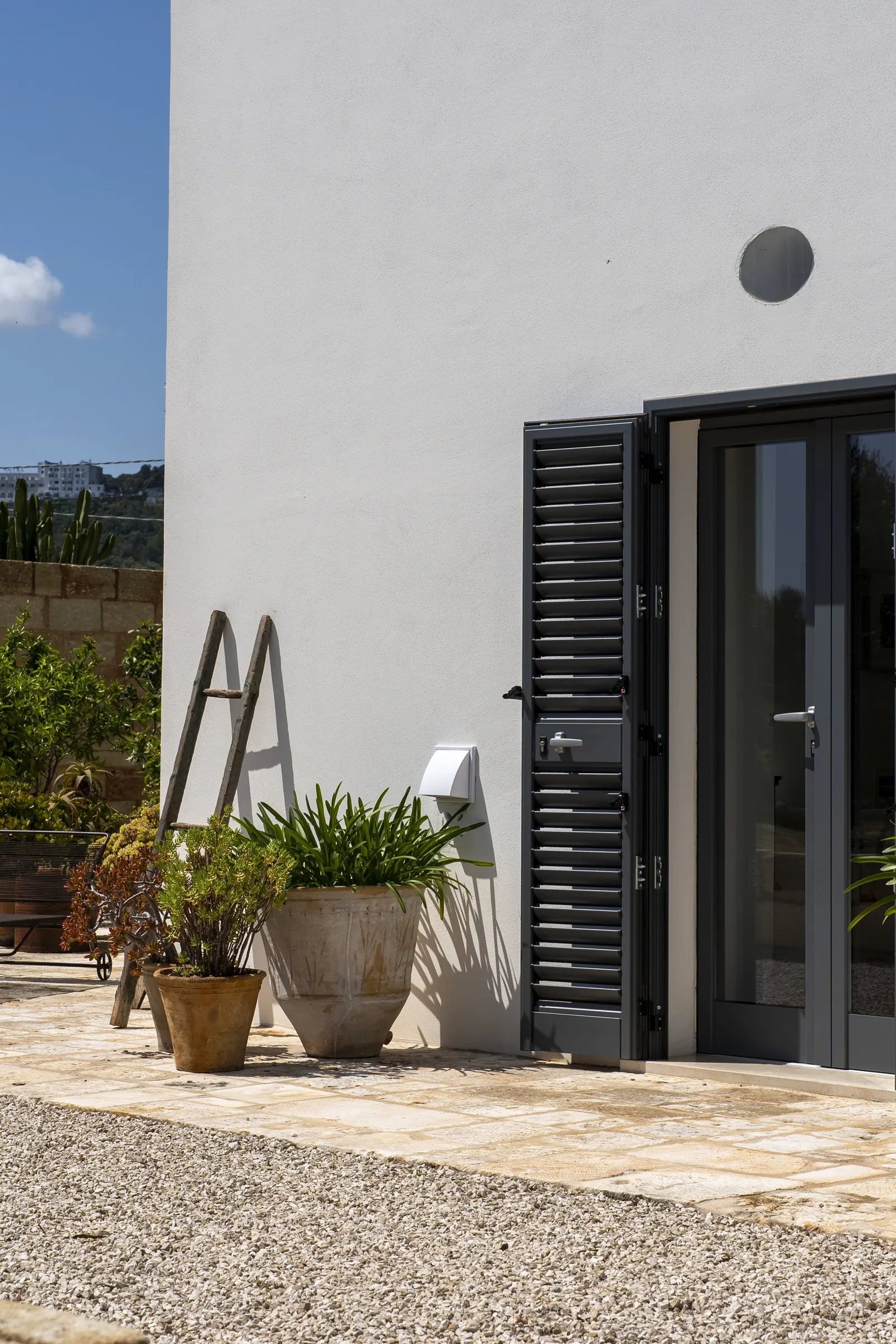 Villa entrance with shutters and potted plants